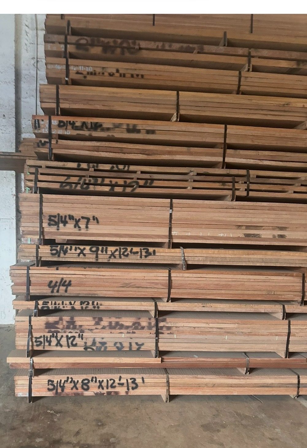 Stacked hardwood lumber inventory showing 4/4 and 5/4 boards in multiple widths at International Plywood Miami