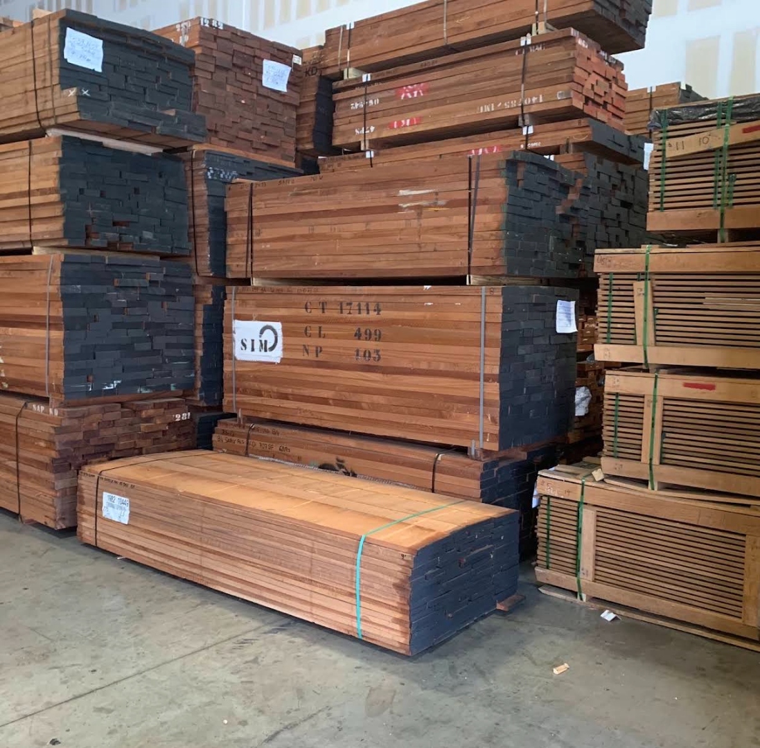 Hardwood lumber bundles stacked in warehouse — 5/4 mahogany boards in various widths at International Plywood Miami