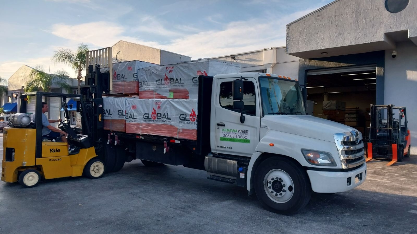 Yale forklift loading fire-retardant FRT plywood onto International Plywood delivery truck at Doral warehouse